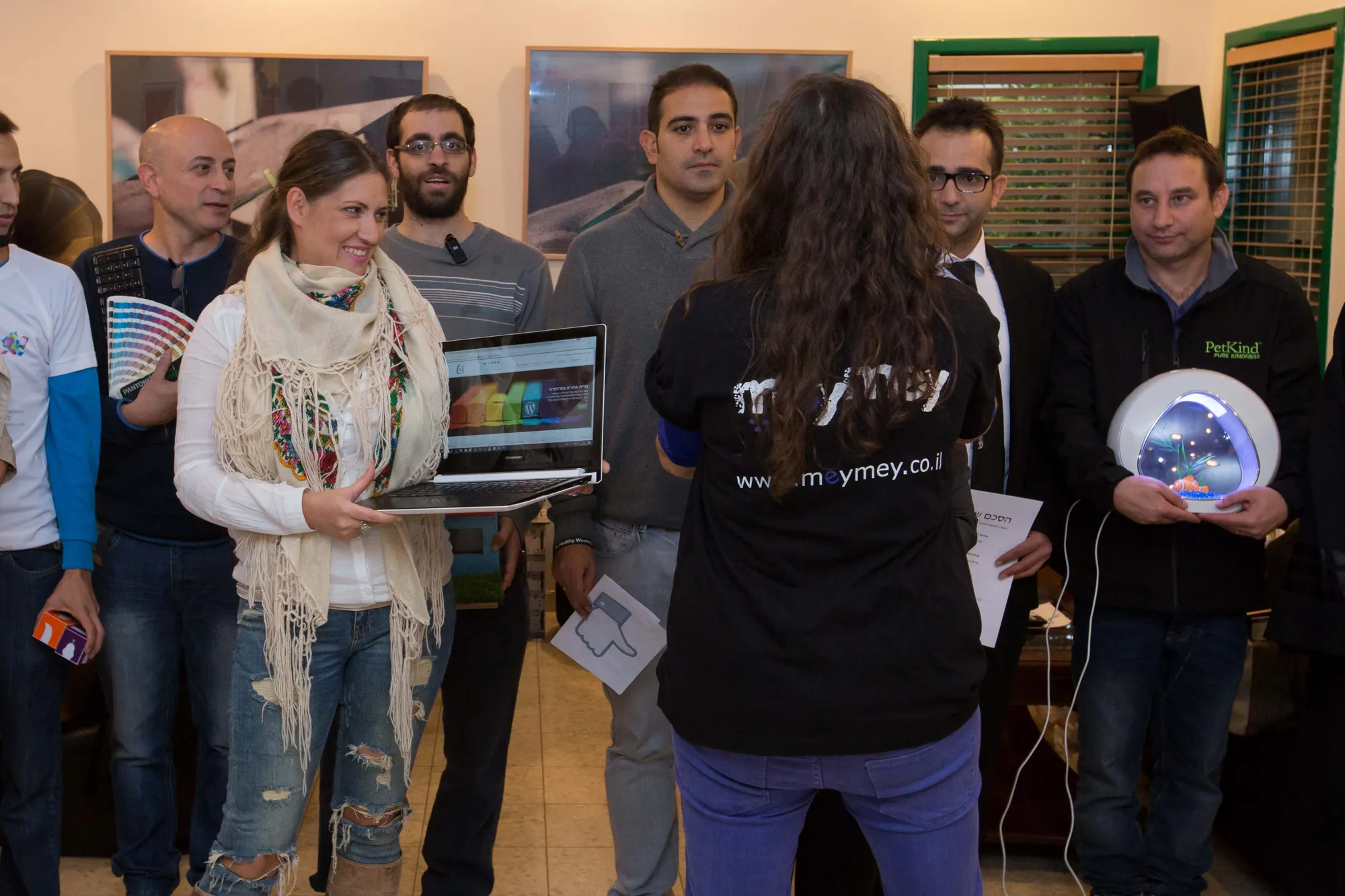 מיי מיי סגל מביימת קבוצת משתתפים שמחזיקים אביזרים מול המצלמה