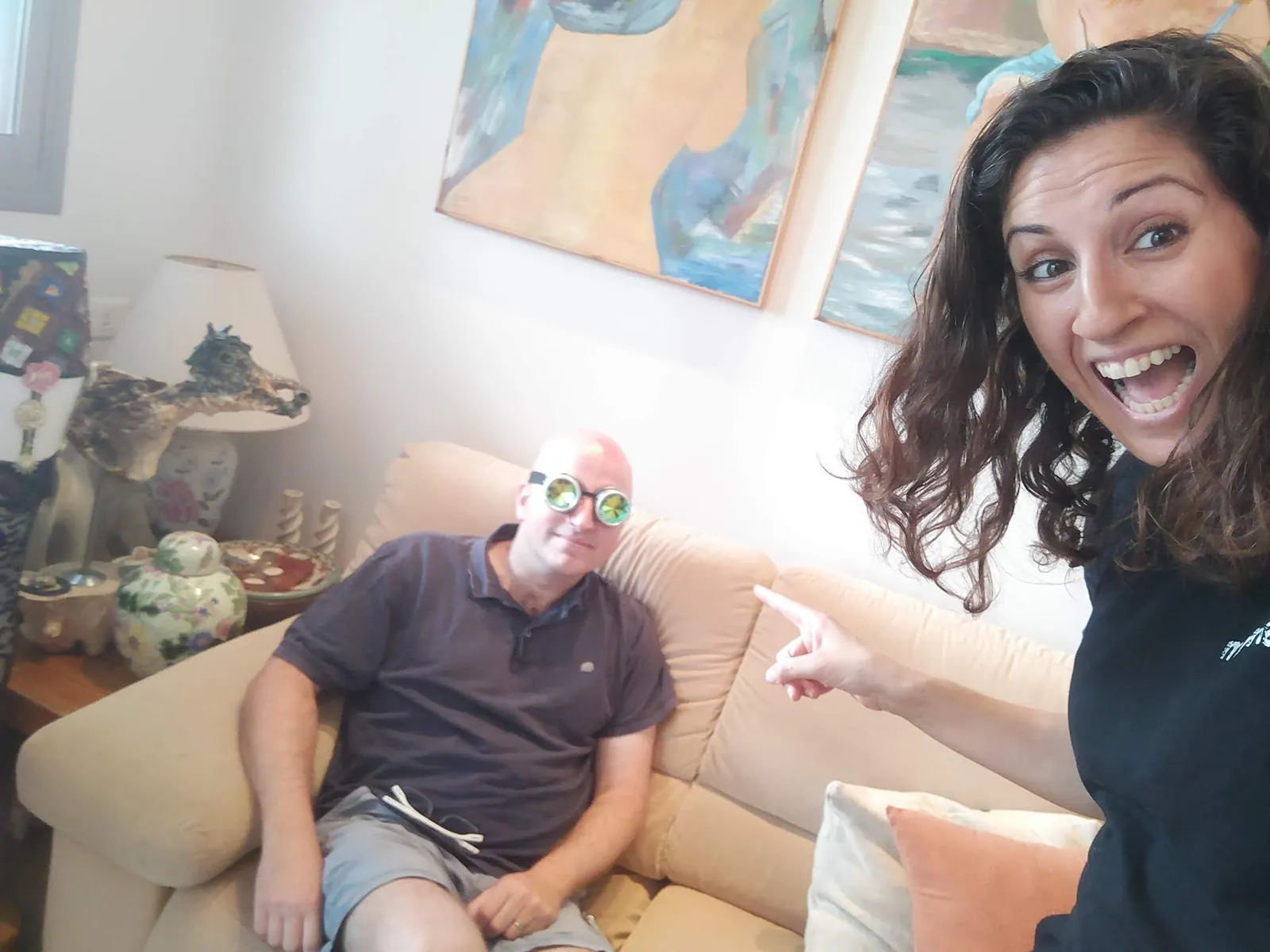 מיי מיי סגל מצביעה על גבר במסכה צבעונית שיושב על ספה