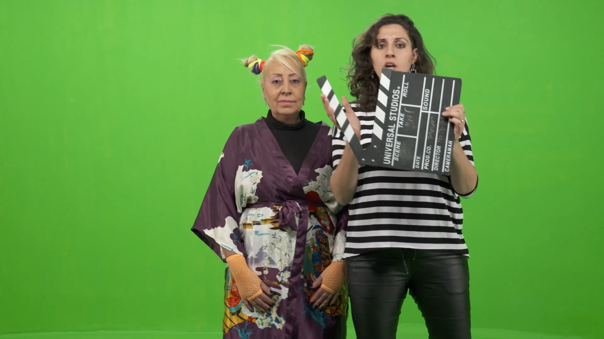 מיי מיי סגל מחזיקה קלאפר לצד שתי משתתפות באולפן מסך ירוק