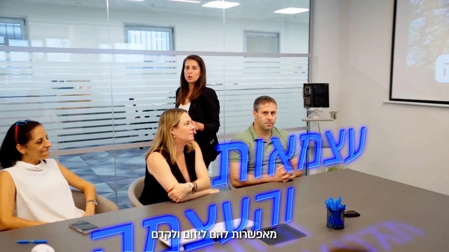 קדר מתוך סרט מיתוג מעסיק שהפקנו למדטכניקה — ארבעה עובדים סביב שולחן ישיבות, אחת מהן עומדת ומדברת אליהם, ועל הקדר כותרת כחולה «עצמאות והעצמה»
